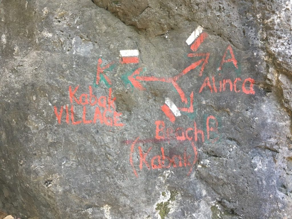Painted directions on boulder at 3-way merge point above Kabak Beach.